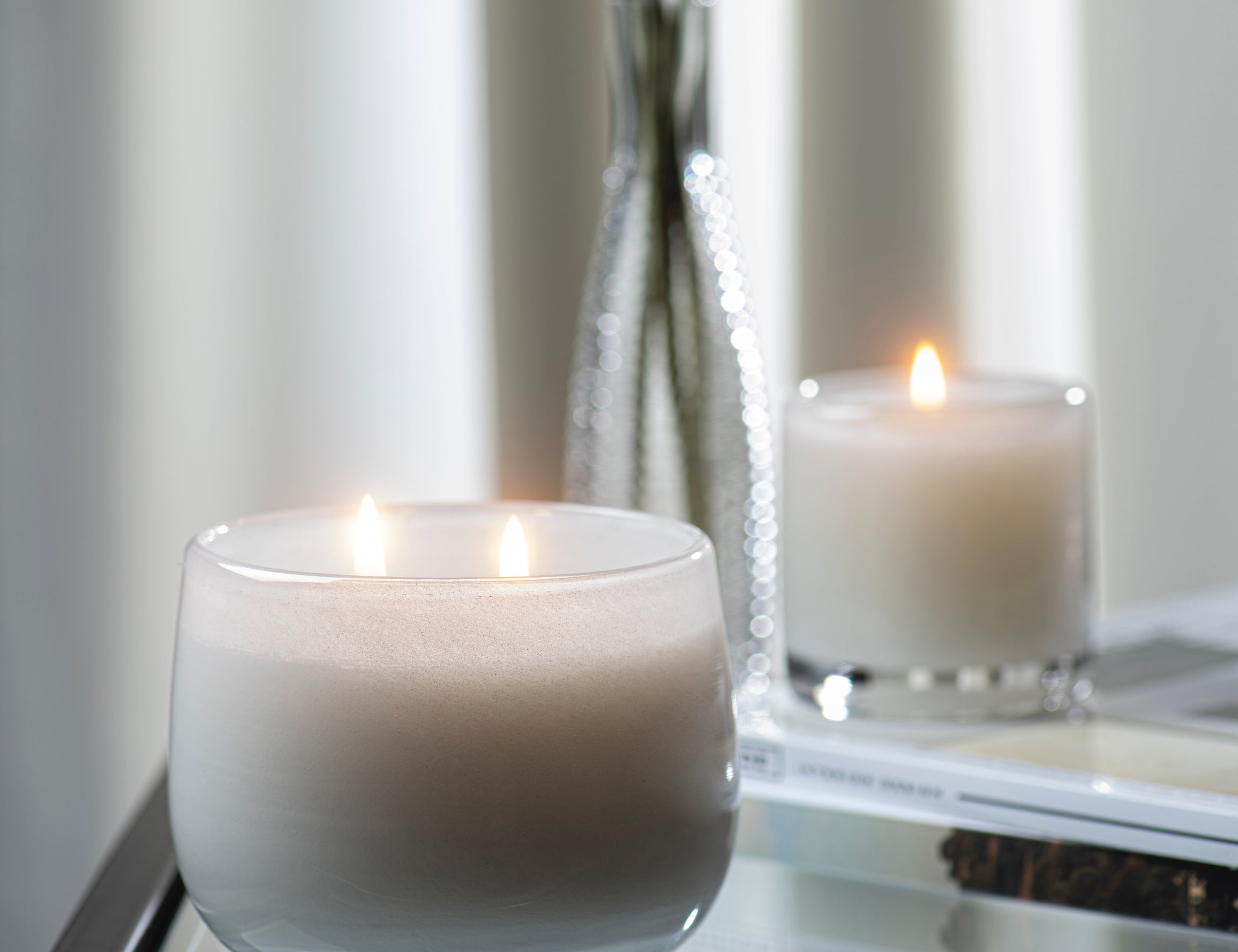 Paris inspired Salon De Tabac white two wick candle by Alixx with earthy oak wood, warm bourbon, and sweet plum nectar fragrance.  Set in white and silver interior.