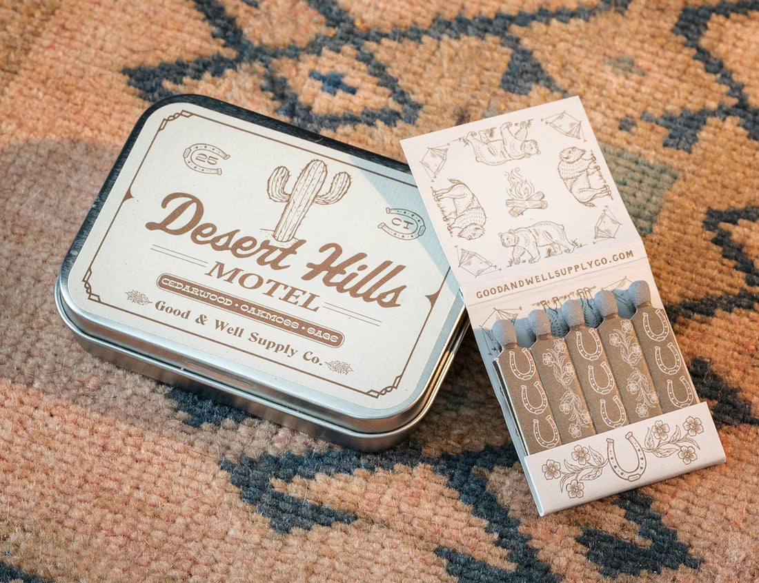 Desert Hills Motel Incense and vintage inspired motel matchbook by Good & Well Supply Co in tan and brown design resting on Southwestern patterned rug. 