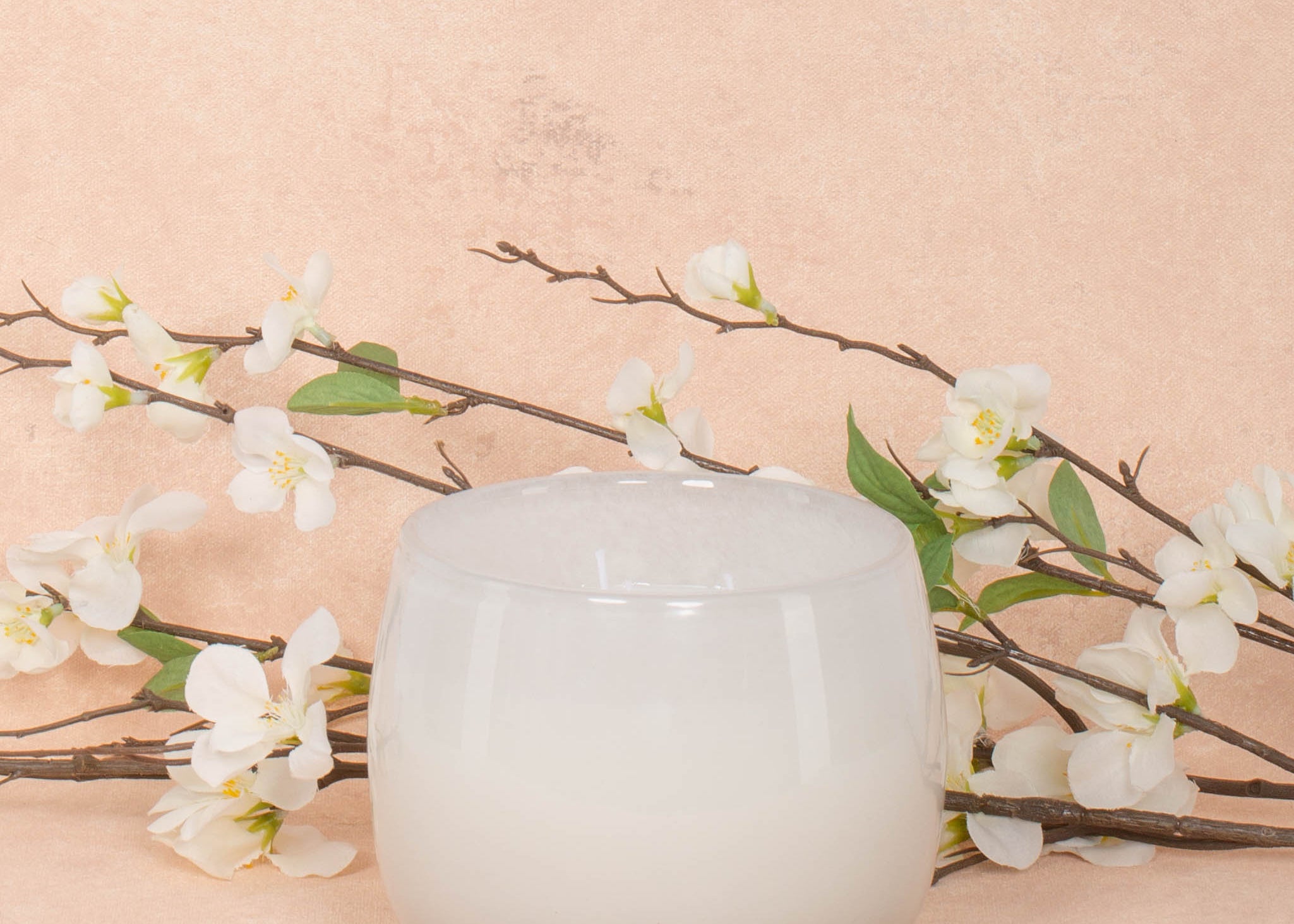 16oz Heure du Thé Ballon candle by Alixx in white. Lily of the valley, water cedar, and musk fragrance. White flowers and pink background behind.