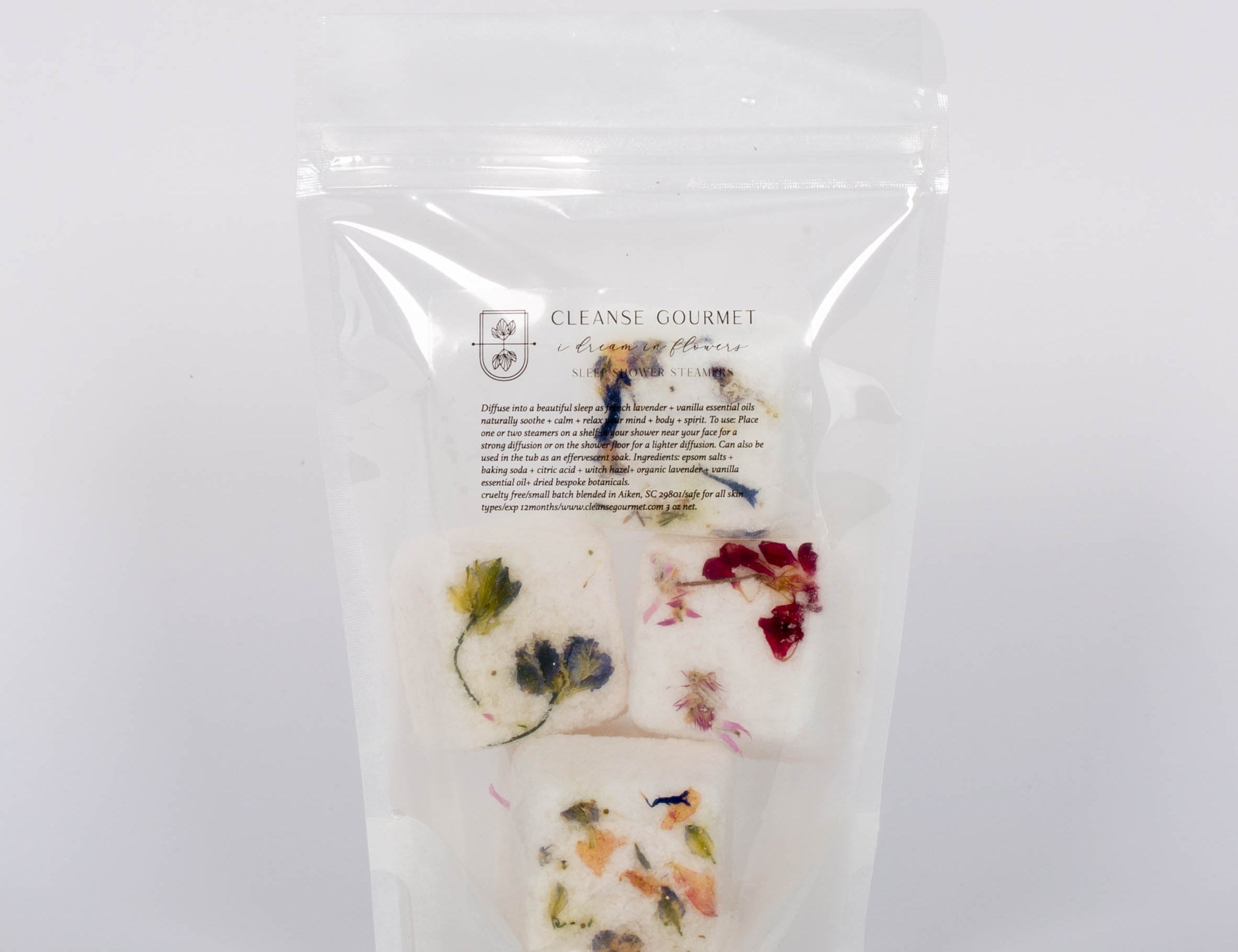 I Dream in Flowers Botanical Shower Steamers by Cleanse Gourmet with French lavender and vanilla essential oils. Four white and floral cubes in clear packaging in front of white background.