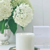 Fleur Blanche Cylindre white bubble glass candle by Alixx with moonflower and violet aroma. Hydrangeas bouquet and white interior setting. 