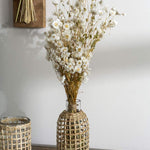 Two Jaxon Caraffes made of rattan covered glass, set in home and holding dried white flowers.