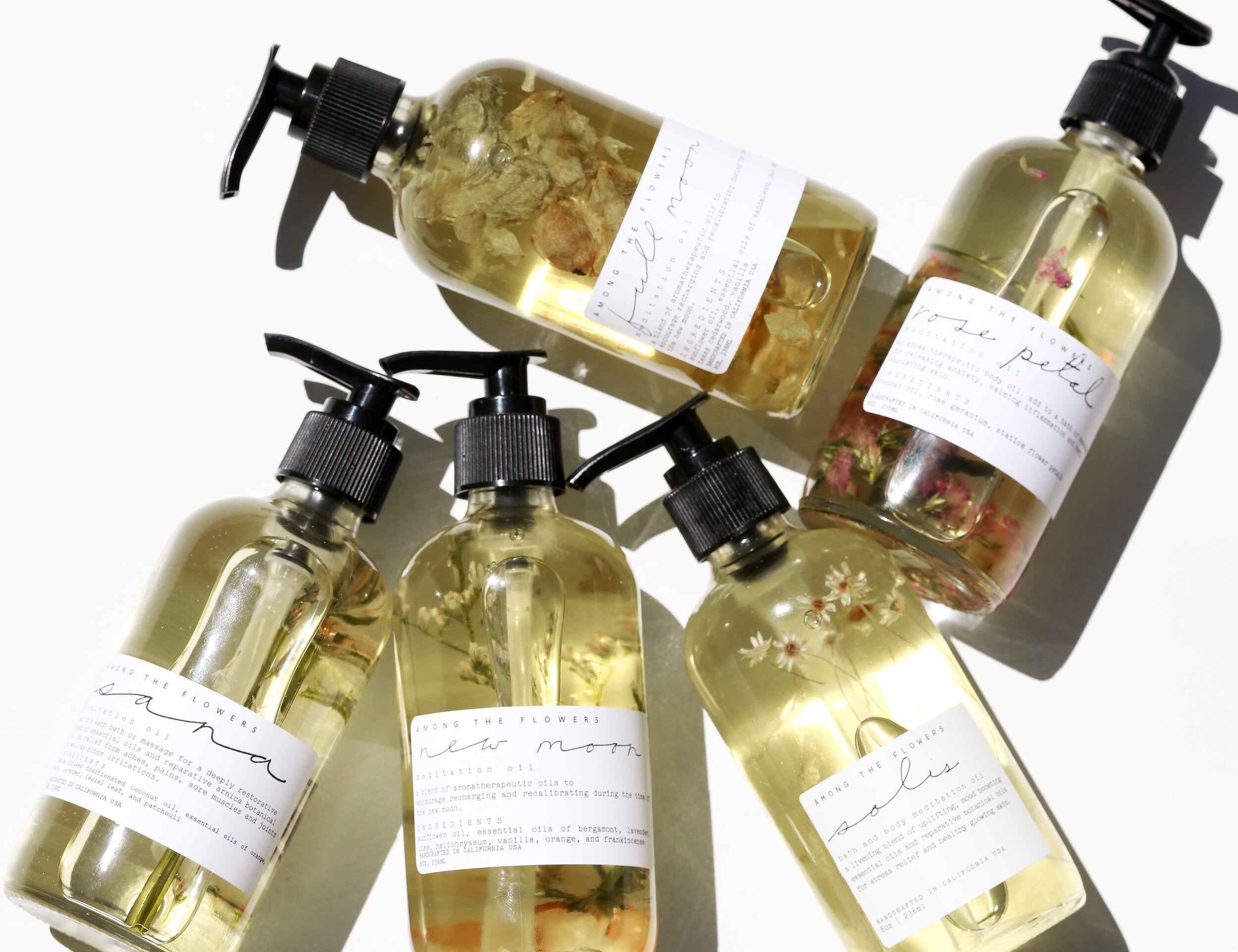 Rose Petal Body Oil and five other premium body oils by Among the Flowers in clear spray bottles. 