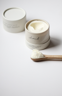Among the Flowers Tallow Body Cream in an open white jar with a wooden spoon of cream