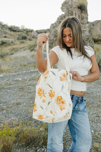 Model opening the Desert Sol Carryall Tote in Apricot Floral