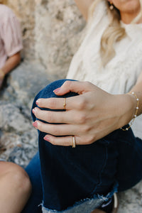 Model wearing the Desert Sol Solara pearl bracelet in gold and Canyon Marquise Ring, hand resting on her knee