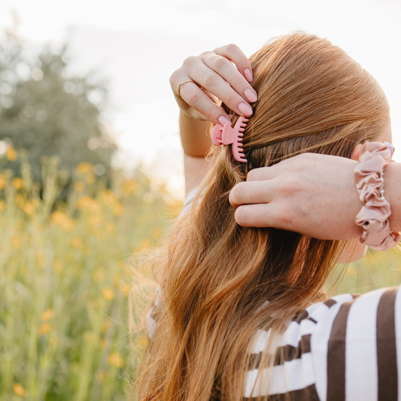 Pink Frenchie claw clip and blush silk scrunchie from the Desert Sol Collection, worn in long hair outdoors in Moab, Utah