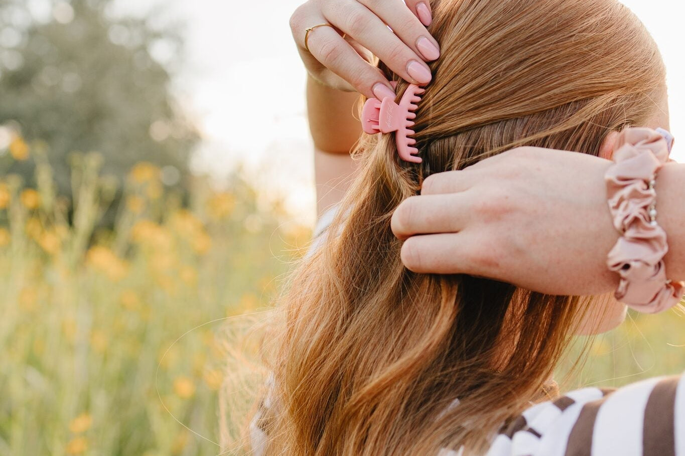 Pink Frenchie claw clip and blush silk scrunchie from the Desert Sol Collection, worn in long hair outdoors in Moab, Utah