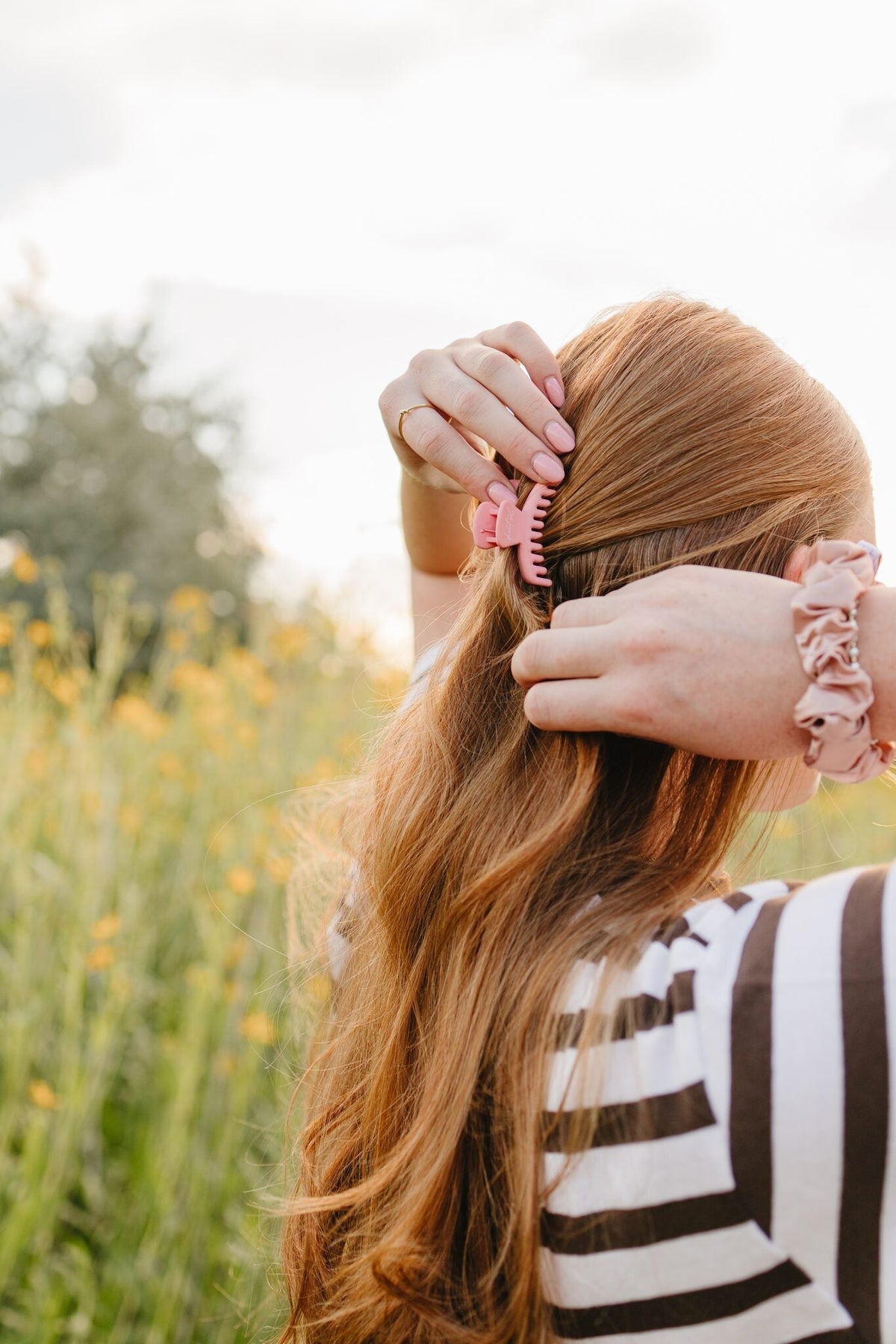 Pink Frenchie claw clip and blush silk scrunchie from the Desert Sol Collection, worn in long hair outdoors in Moab, Utah