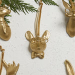 E + E Ornaments, sixteenth view, the gold mouse with a bow tie beside cedar greenery