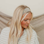 Woman with long blonde hair wearing a striped headband against a neutral background