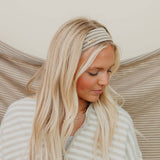 Woman with long blonde hair wearing a striped headband against a neutral background