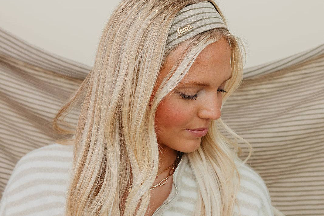Woman with long blonde hair wearing a striped headband against a neutral background