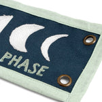 Close-up of the embroidered moon phases and brass grommet on the 1canoe2 Find Beauty Banner