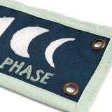 Close-up of the embroidered moon phases and brass grommet on the 1canoe2 Find Beauty Banner