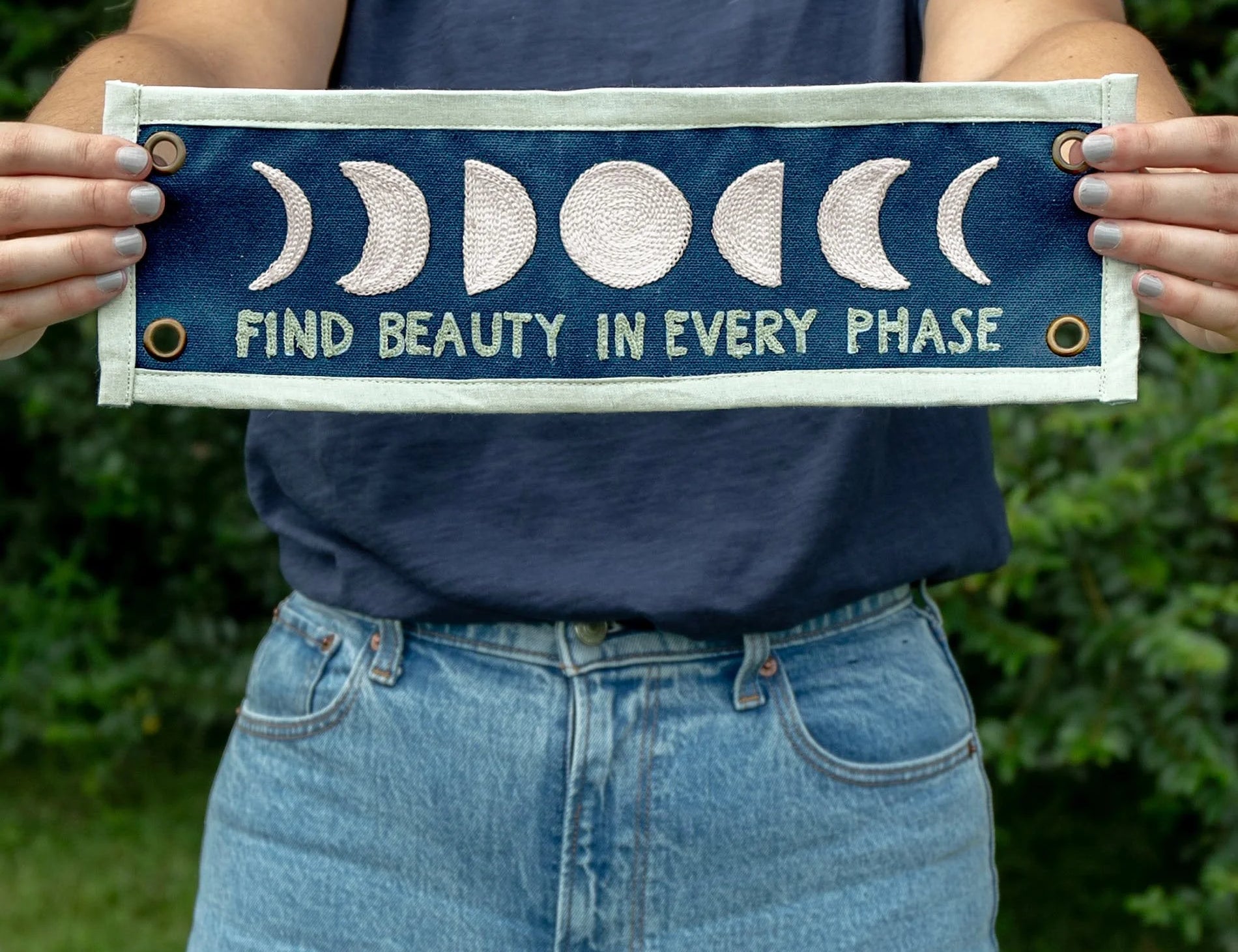 Person holding the 1canoe2 Find Beauty in Every Phase banner outdoors