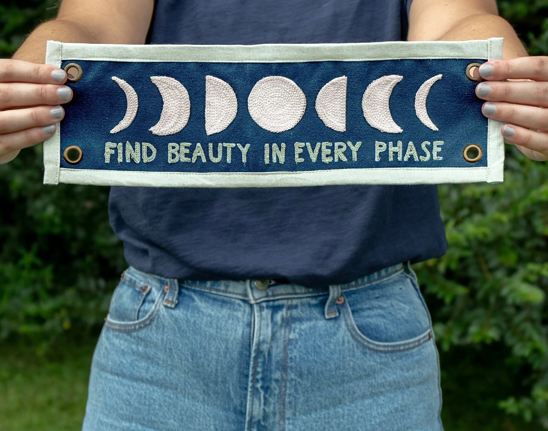 Person holding the 1canoe2 Find Beauty in Every Phase banner outdoors