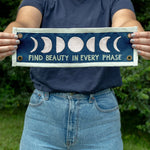 Person holding the 1canoe2 Find Beauty in Every Phase banner outdoors