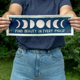 Person holding the 1canoe2 Find Beauty in Every Phase banner outdoors