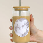 Hand holding the 1canoe2 Moon Phases Glass Can filled with an iced latte