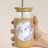 Hand holding the 1canoe2 Moon Phases Glass Can filled with an iced latte