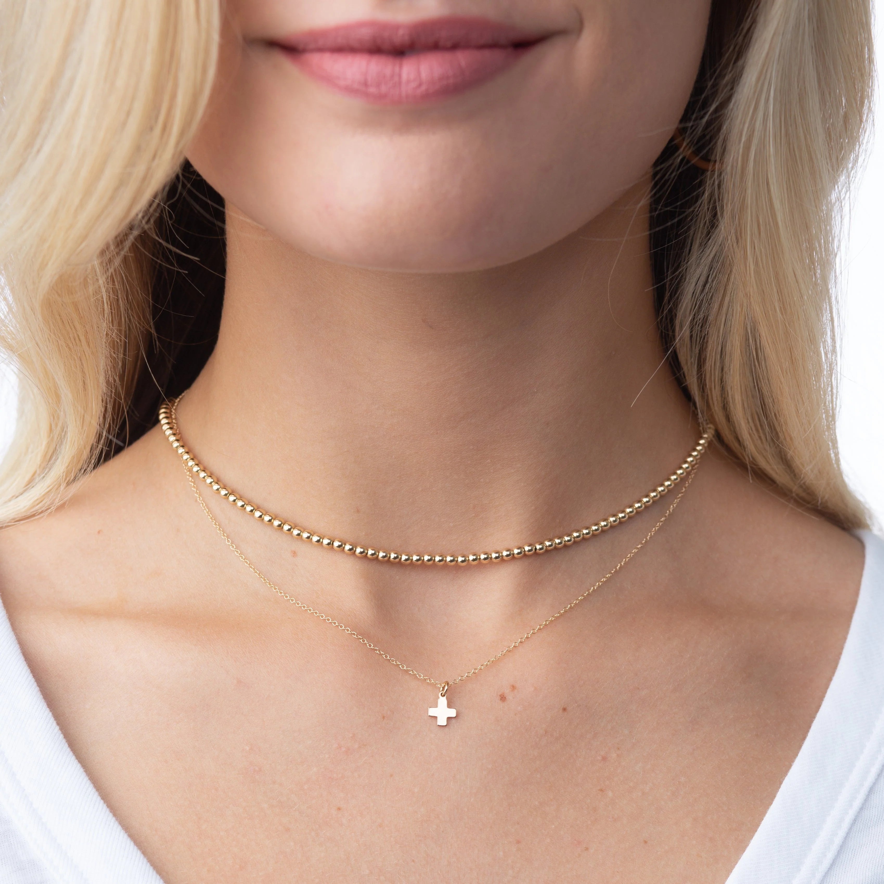 Woman wearing double chain necklaces with small cross pendant and beads