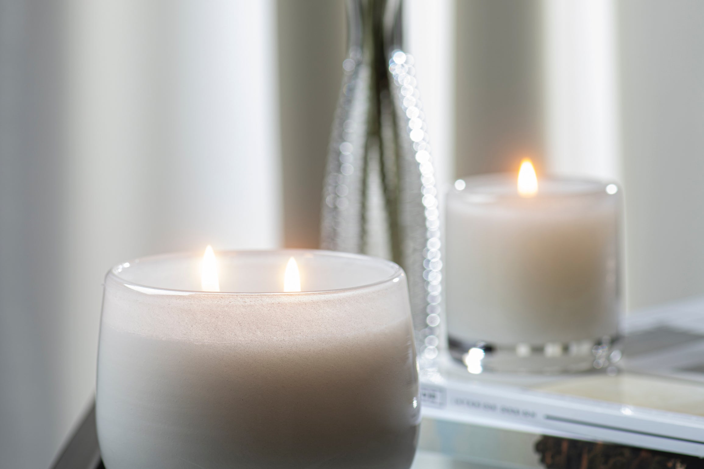 Paris inspired Salon De Tabac white two wick candle by Alixx with earthy oak wood, warm bourbon, and sweet plum nectar fragrance.  Set in white and silver interior.