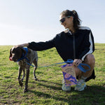 Woman with a dog on a leash in a grassy field
