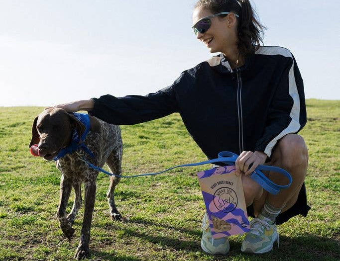 Woman with a dog on a leash in a grassy field