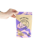Hand holding a package of 'Winnie Lou' dog treats with a purple and yellow design.