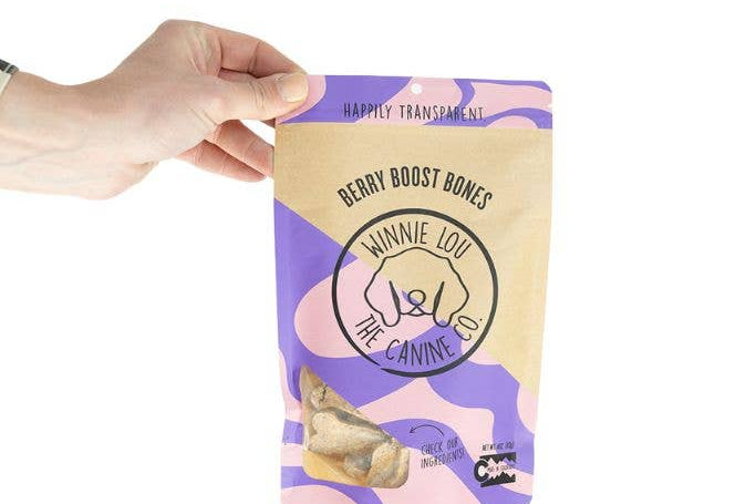 Hand holding a package of 'Winnie Lou' dog treats with a purple and yellow design.