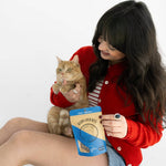 Woman holding a cat and a bag of cat food on a white background