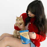 Woman holding a cat and a bag of cat food on a white background