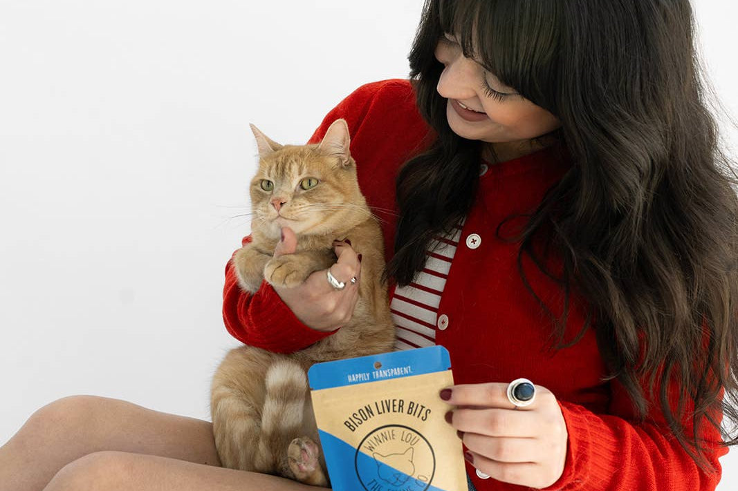 Woman holding a cat and a bag of cat food on a white background