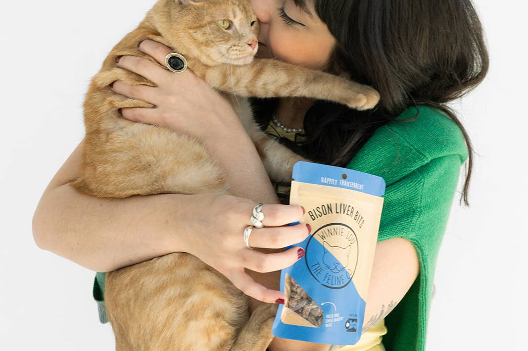 Woman holding a cat and a can of food against a white background