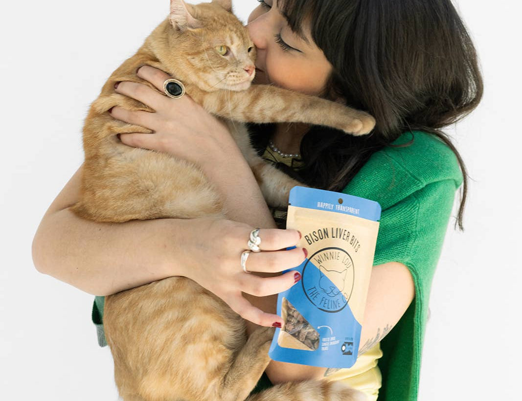 Woman holding a cat and a can of food against a white background