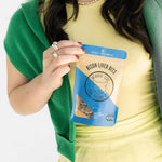 Person holding a package of 'Winnie the Winnie' bison liver bits against a white background