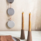 Set of two reddish brown terracotta Canyon Candleholders by Citrine holding natural gold yellow candles. 
