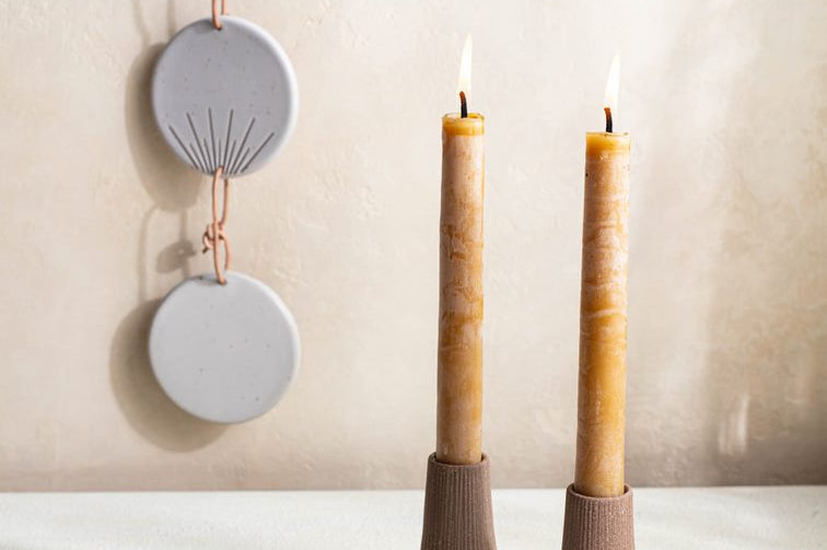 Set of two reddish brown terracotta Canyon Candleholders by Citrine holding natural gold yellow candles. 