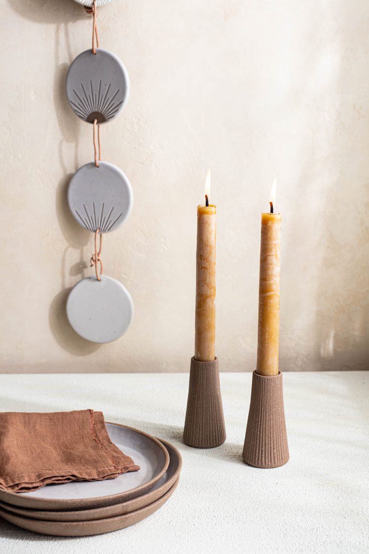 Set of two reddish brown terracotta Canyon Candleholders by Citrine holding natural gold yellow candles. 