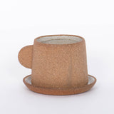 Canyon Clay Cup and Saucer with small handle by Citrine made from exposed reddish-brown earthenware and finished with a thin off-white glaze. 