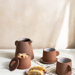 Canyon Clay Cup and Saucer shown with whole set by Citrine along with sugar cubes and desert. 
