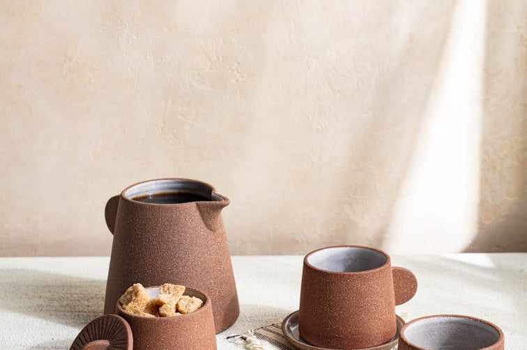 Canyon Clay Cup and Saucer shown with whole set by Citrine along with sugar cubes and desert. 