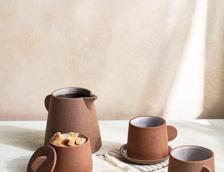 Canyon Clay Cup and Saucer shown with whole set by Citrine along with sugar cubes and desert. 