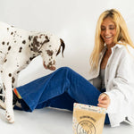 Woman sitting on the floor with a Dalmatian dog and a bag of dog treats.