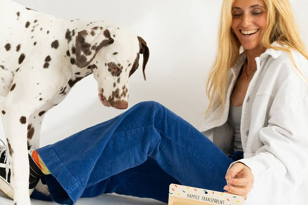 Woman sitting on the floor with a Dalmatian dog and a bag of dog treats.