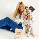 Woman sitting on a white surface with a Dalmatian dog and a package of treats.