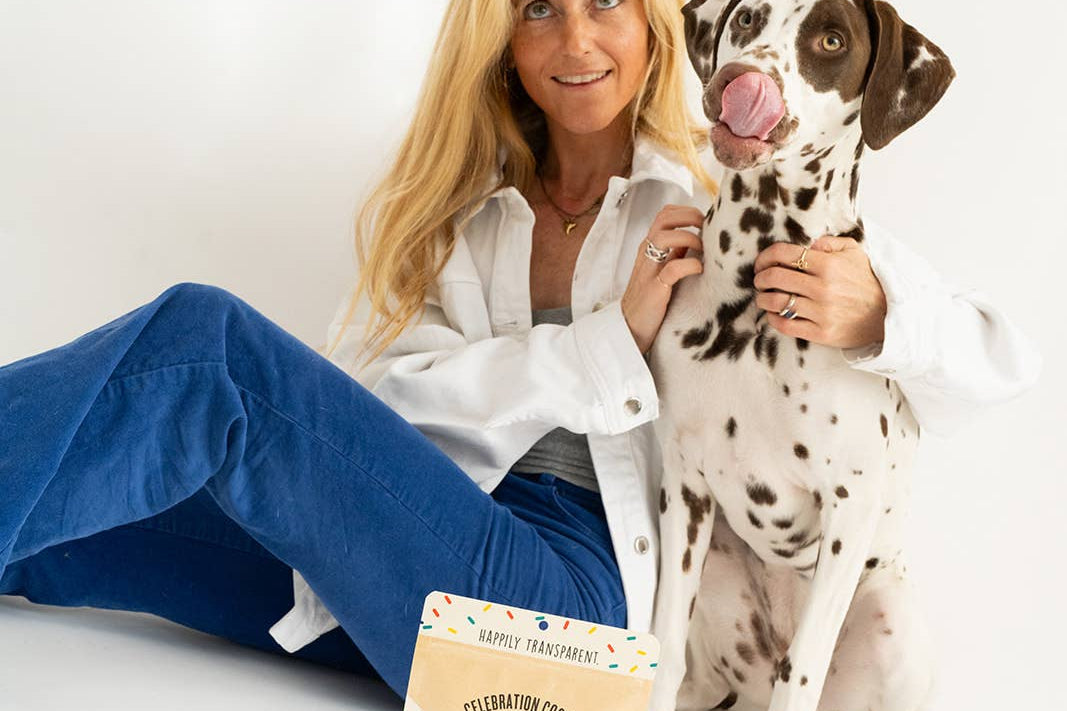 Woman sitting on a white surface with a Dalmatian dog and a package of treats.