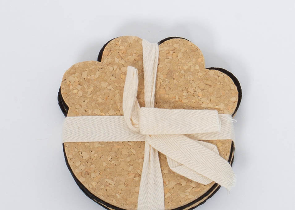 100% Recycled Dog Paw Rubber Coaster Set in tan and black by Ore Originals tied together with cream ribbon.