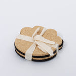 100% Recycled Dog Paw Rubber Coaster Set in tan and black by Ore Originals tied together with cream ribbon.